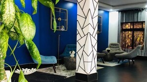Een moderne woonkamer met een blauwe accentmuur, een geometrische pilaar, een bank en een potplant.