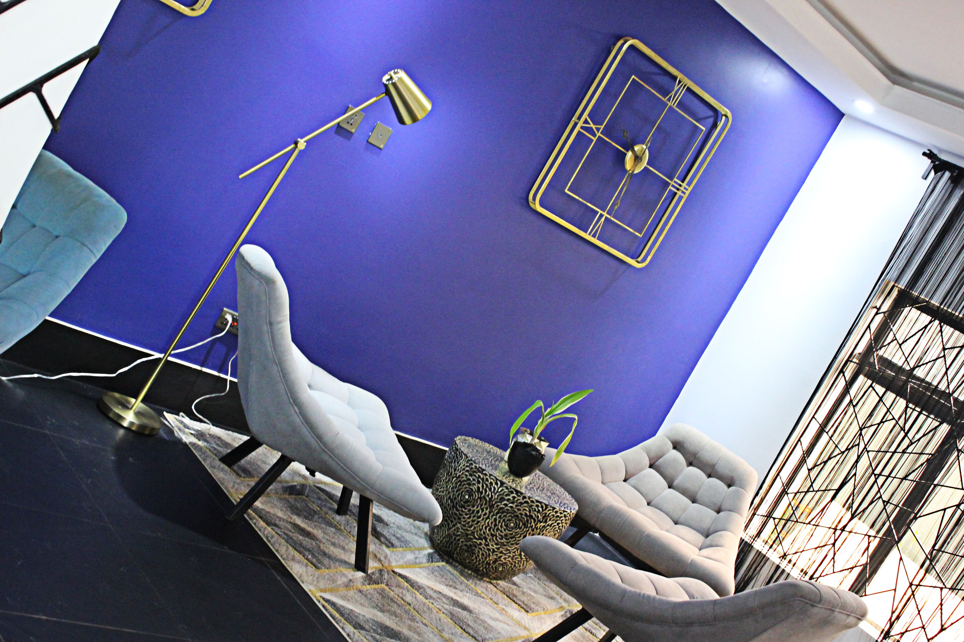 A modern room with a blue accent wall, a patterned rug, and a unique geometric light fixture.