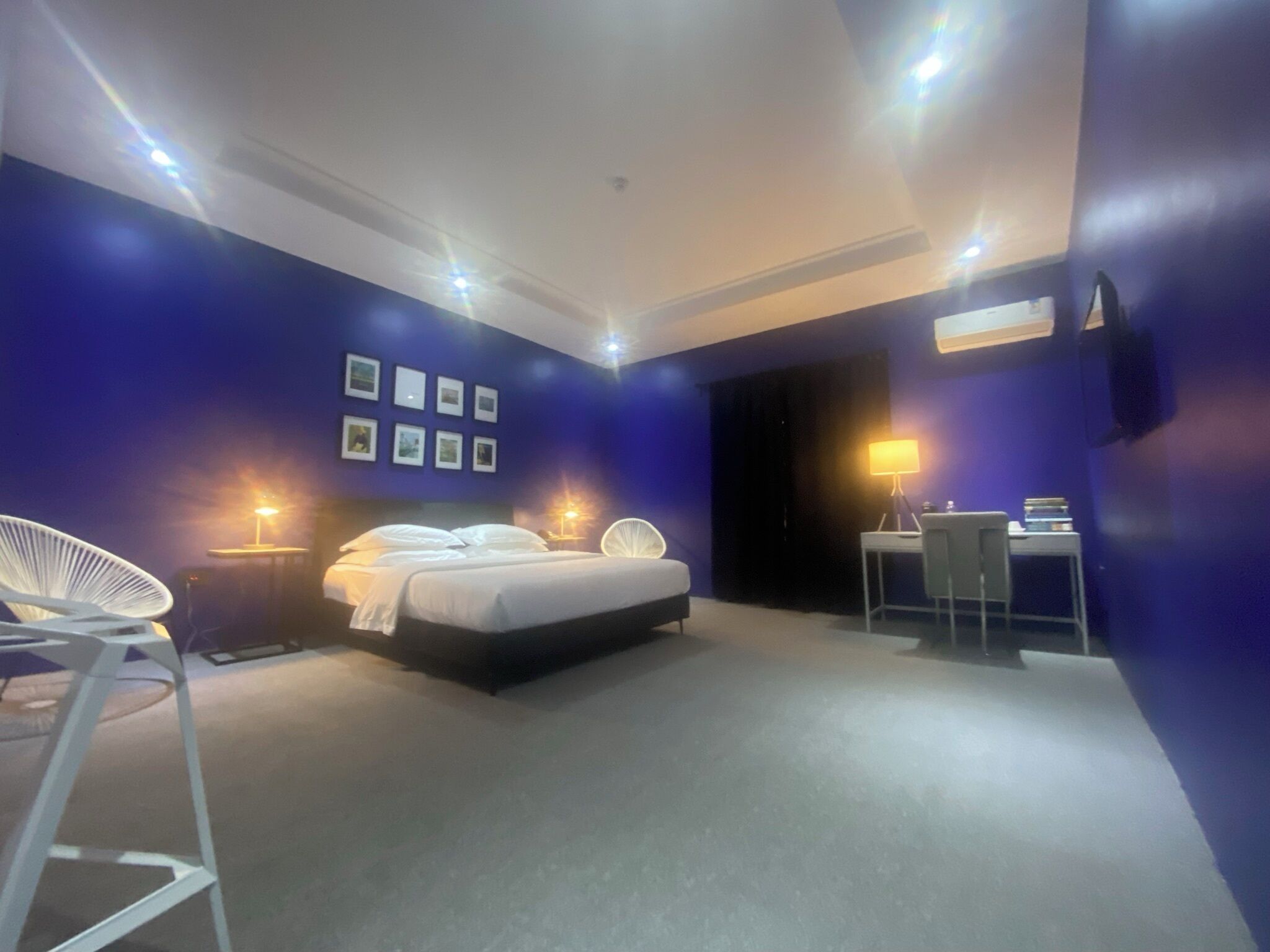 A modern bedroom with a large bed, a desk, and a chair.