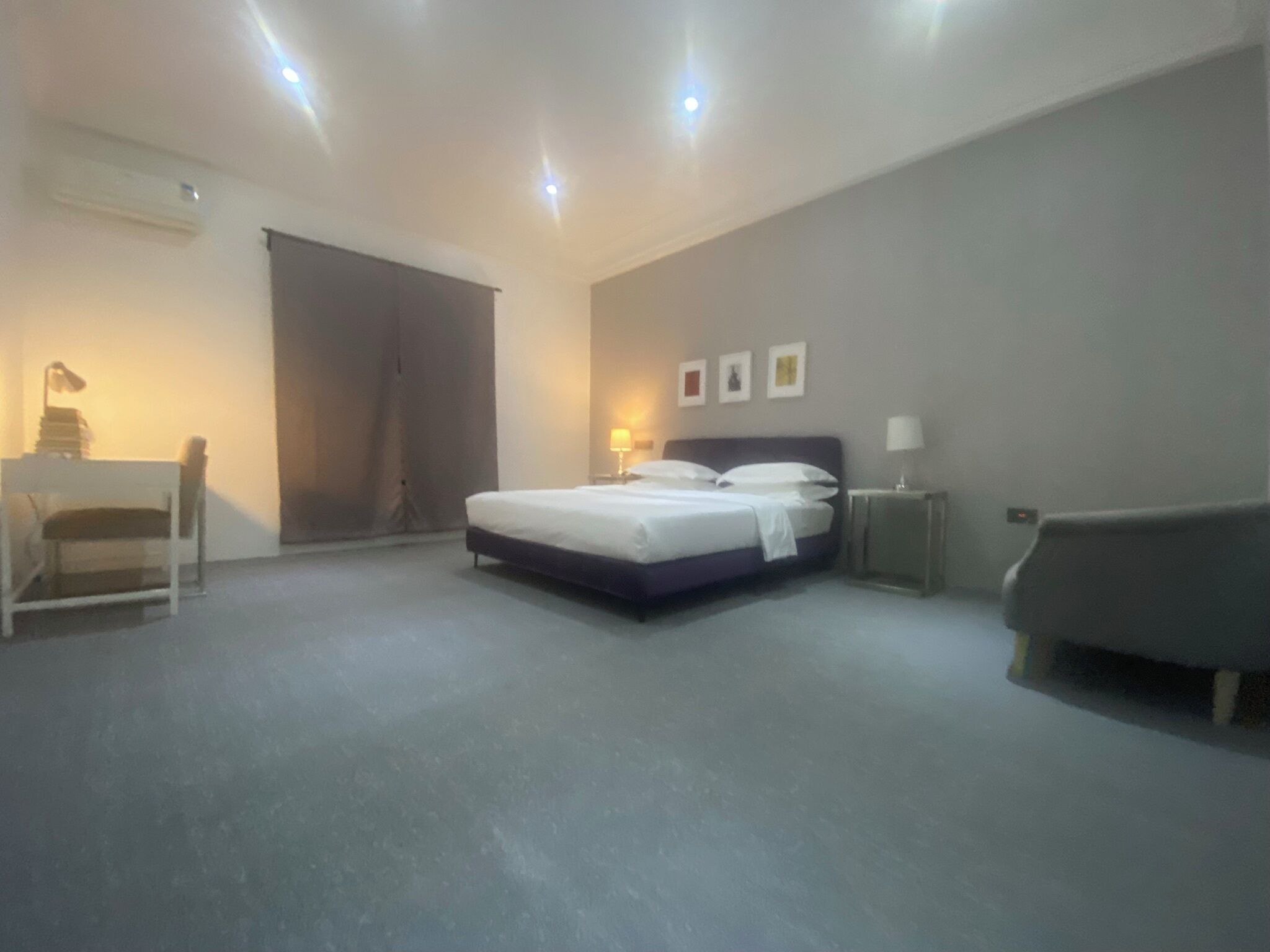 A bedroom with a bed, bedside tables, a desk, and a chair.