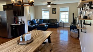 A modern kitchen with a dining area, wooden flooring, and a ceiling fan.