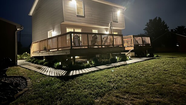 A two-story house with a wooden deck and a covered front porch.