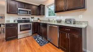 A kitchen with dark wood cabinets, stainless steel appliances, a granite countertop, and a window with a view.