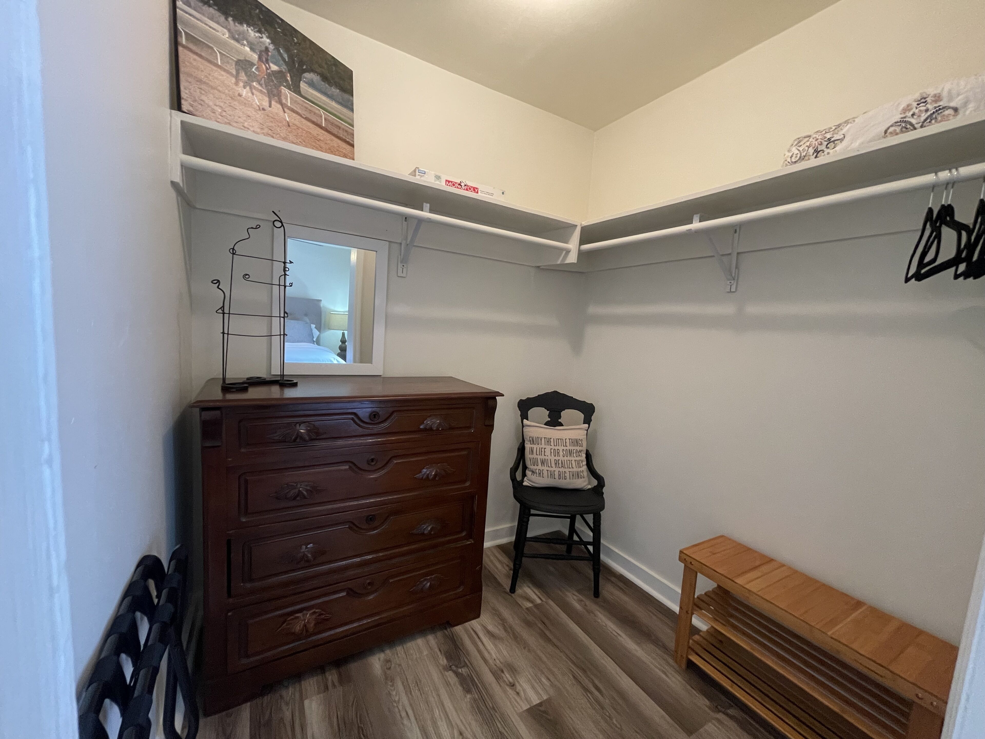 Un petit placard bien aménagé, avec des tiroirs en bois, un miroir et un espace pour suspendre les vêtements.