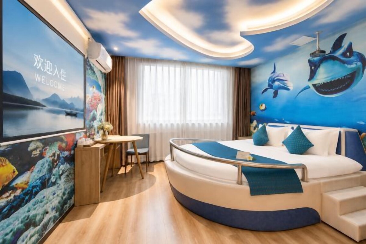 A room with a curved bed, a desk, and a large poster on the wall.