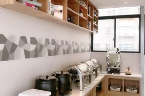 Une cuisine moderne dotée d’un espace dédié au café, comprenant une machine à café, des moulins et des récipients de rangement.