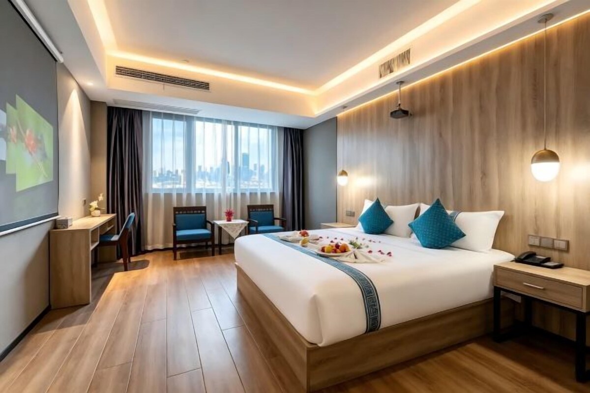 A hotel room with a large bed, bedside table, desk, and chair.