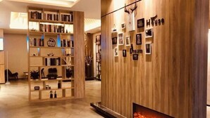 Een modern interieur met een houten boekenkast, een open haard en een wand met ingelijste foto's en de tekst 'Dream House'.