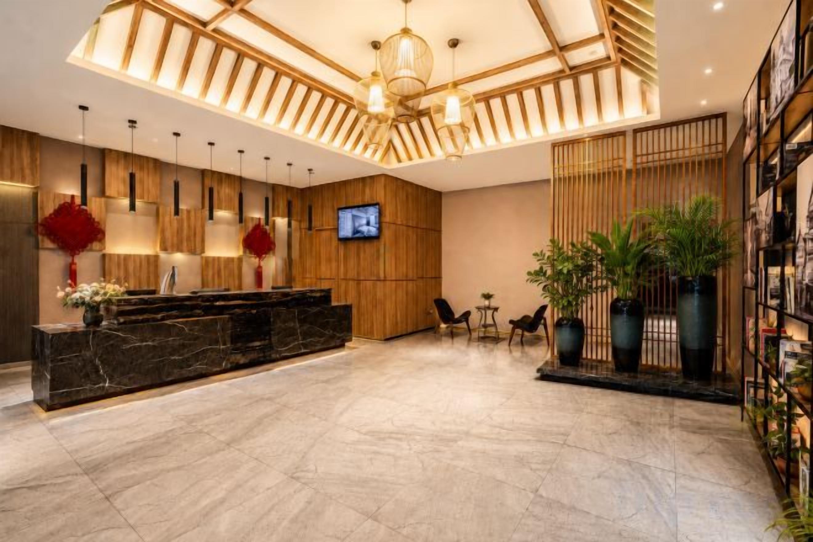 A hotel lobby with a reception desk, seating area, and a TV screen.
