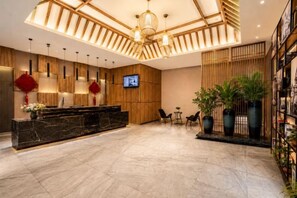 A hotel lobby with a reception desk, seating area, and a TV screen. - Ailove Yahao Hotel (Zhangjiagang)