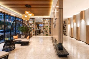 Um hall moderno com área de estar em curva, escadaria central e estante de livros.