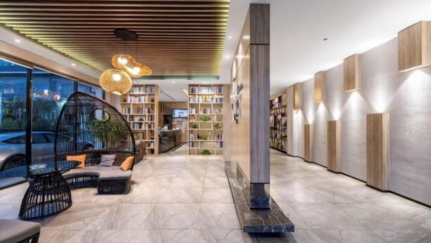 Een moderne lobby met een gebogen zithoek, een open haard en een rij boekenkasten.