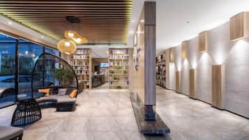 A modern lobby with a fireplace, seating area, and bookshelves.