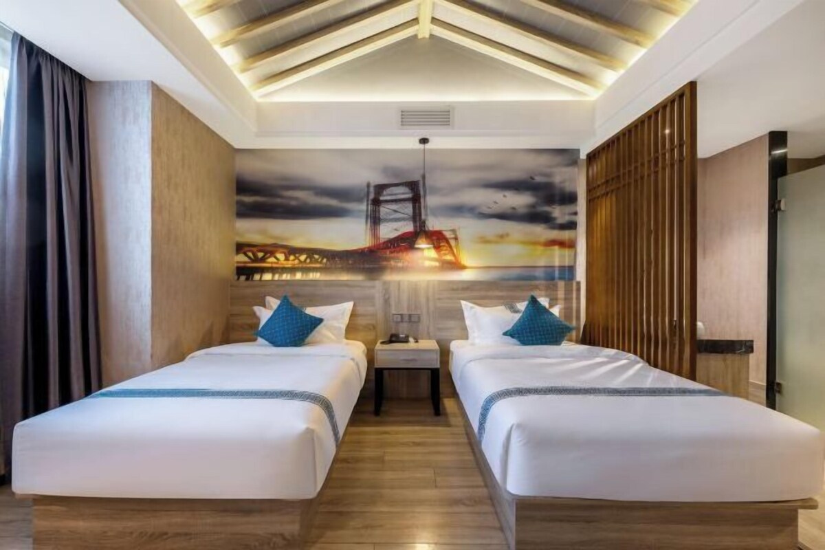Une chambre d’hôtel avec deux lits, une fresque représentant un pont, un plancher en bois et un design moderne au plafond.