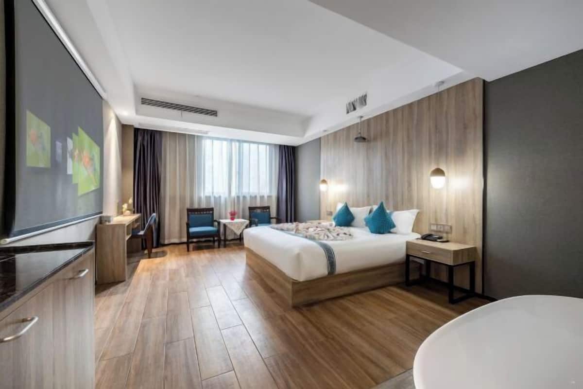 Une chambre d’hôtel moderne avec un grand lit, des tables de chevet, un bureau et une chaise.