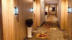 A hotel hallway with wooden paneling, a carpet with floral patterns, and wall-mounted light fixtures. - Ailove Yahao Hotel (Zhangjiagang)