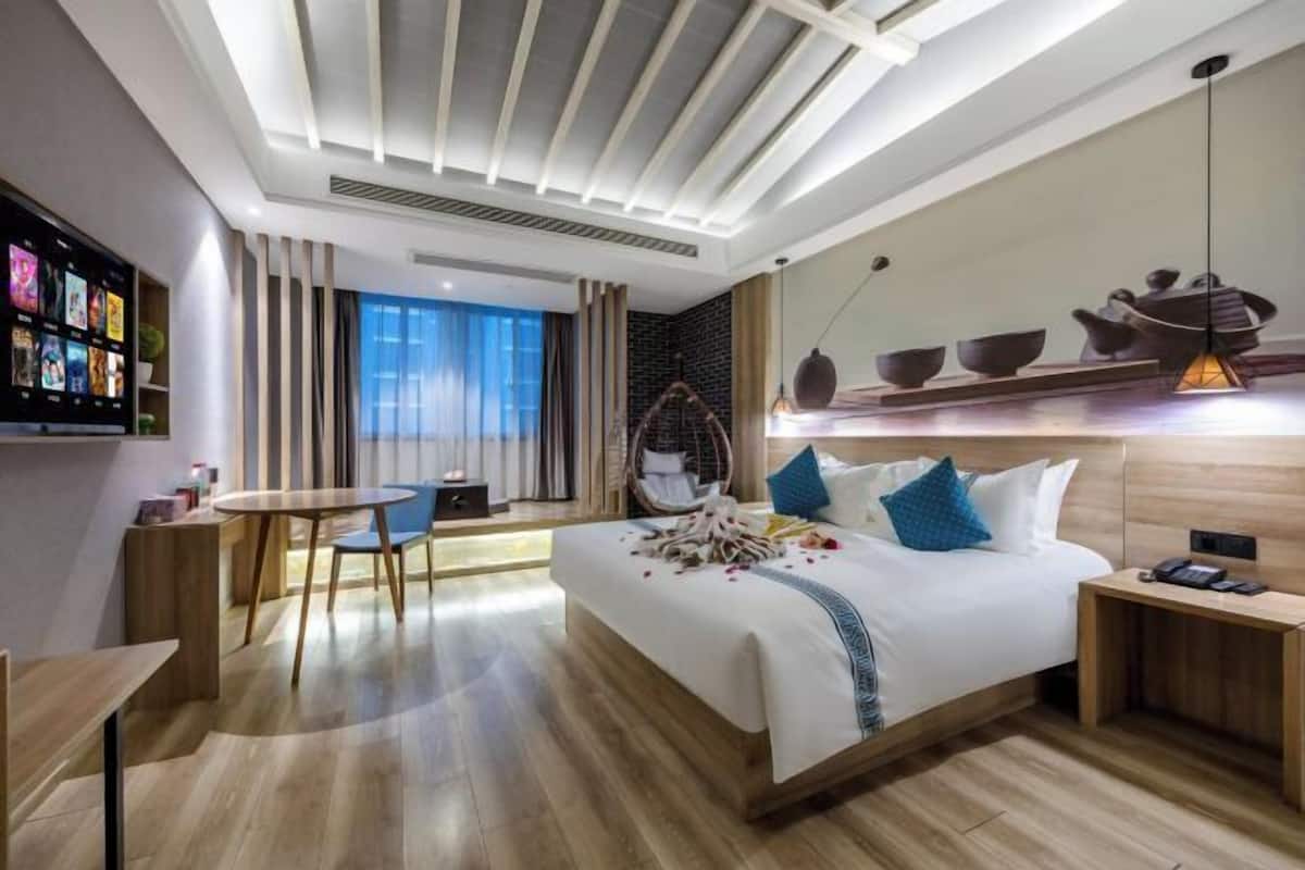 Une chambre d’hôtel moderne, dotée d’un grand lit, d’un bureau, d’une chaise et d’un téléviseur fixé au mur.