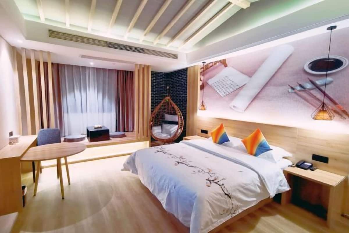 Une chambre d’hôtel moderne équipée d’un grand lit, d’un bureau, d’une chaise et d’un fauteuil suspendu.