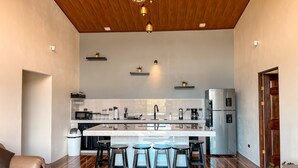 Een moderne keuken met een centraal eiland, barstoelen en een houten plafond.