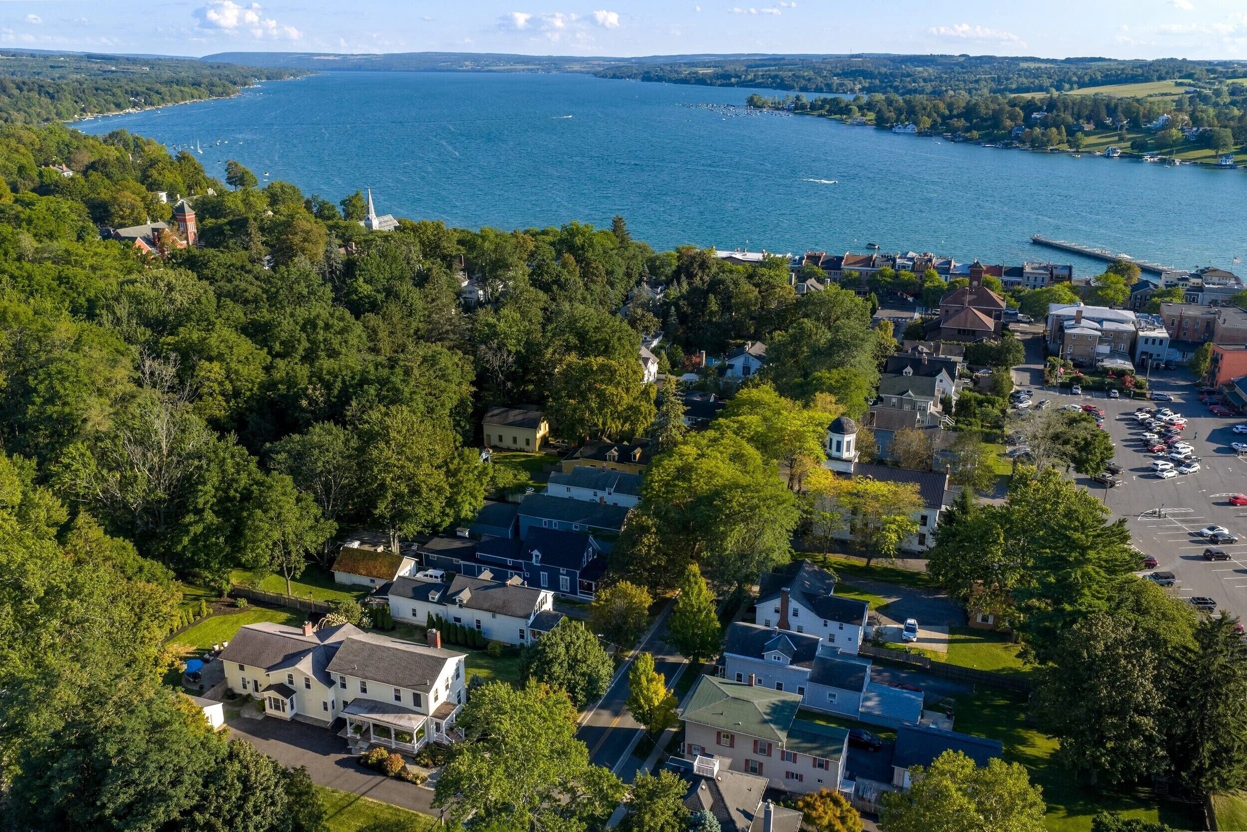 An aerial view of a coastal residential area with houses, a marina, and a church.