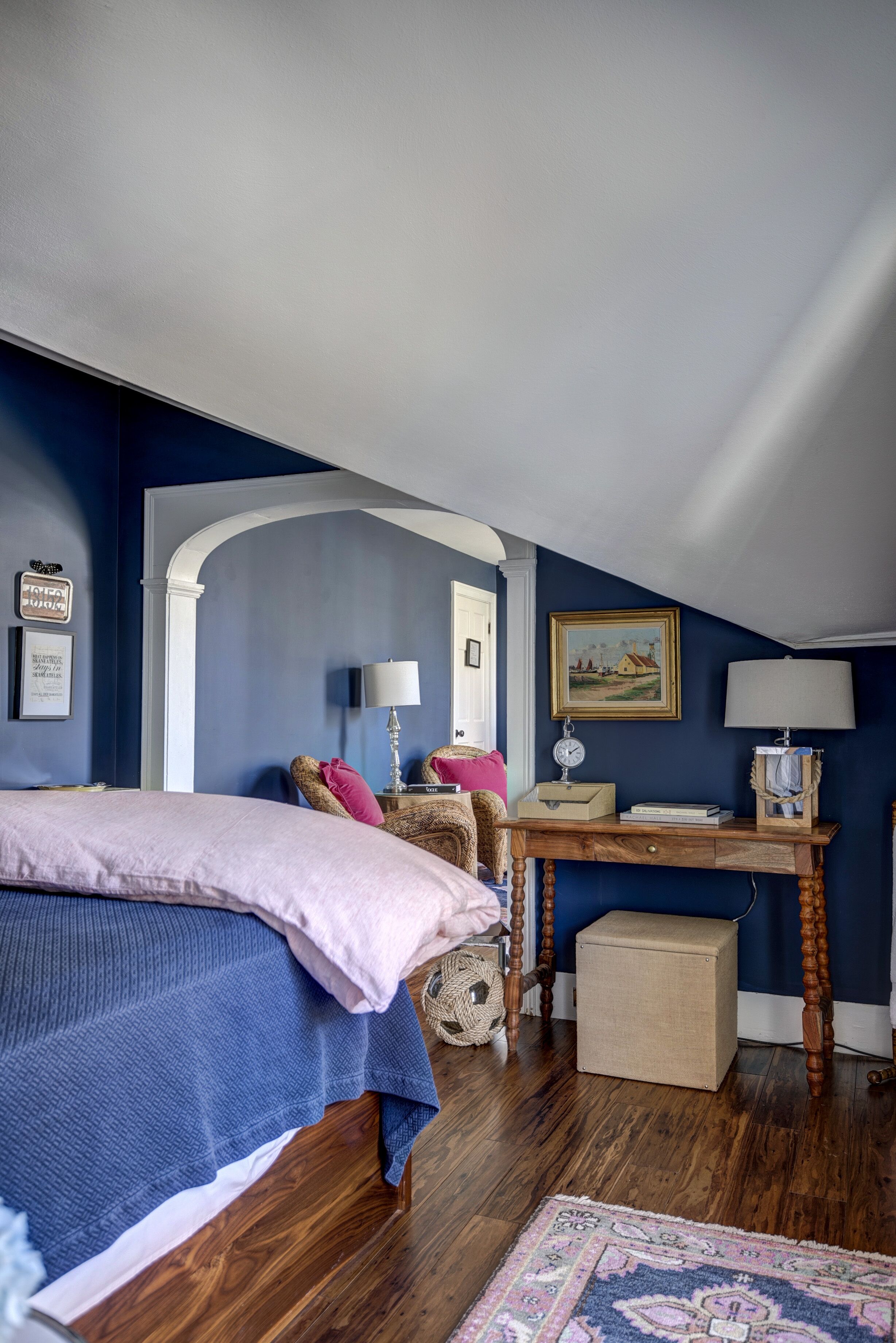 A bedroom with a bed, a desk, a chair, a lamp, and a small cabinet.
