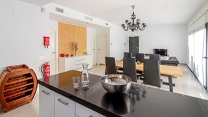 A modern kitchen with a black countertop, a wine rack, and a dining area with a chandelier.
