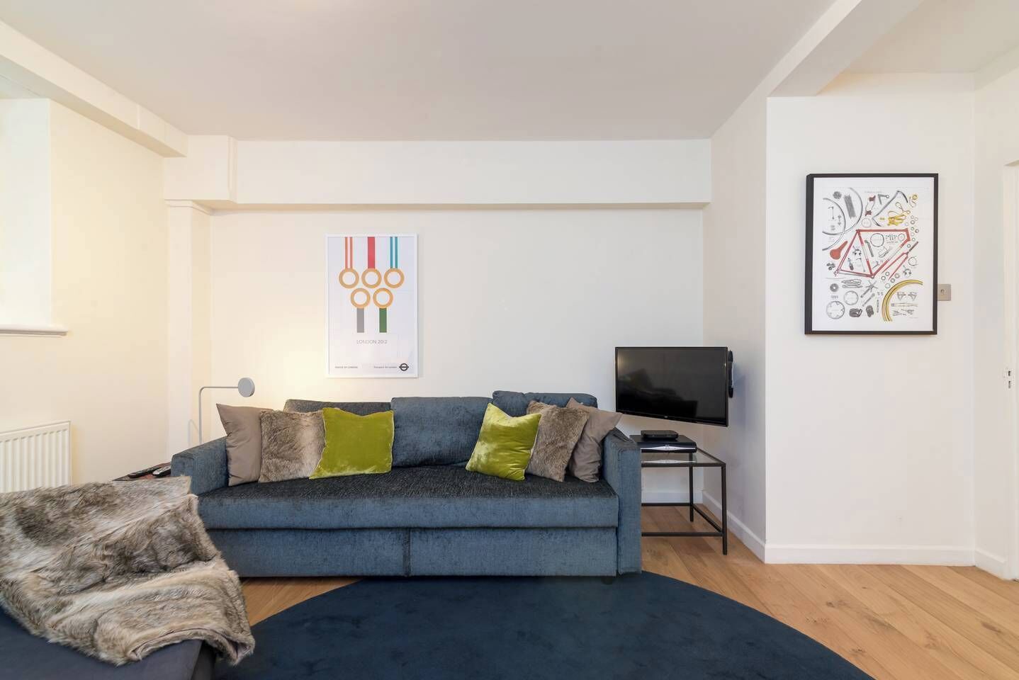 A modern living room with a grey sofa, a flat-screen TV, and artwork on the walls.