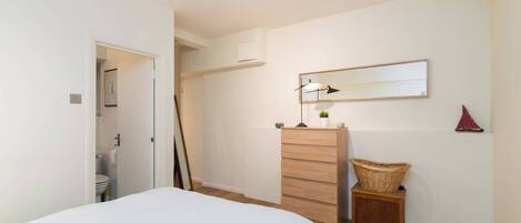 Un dormitorio con una cama, un aparador, un espejo y una mesita de noche con una lámpara.