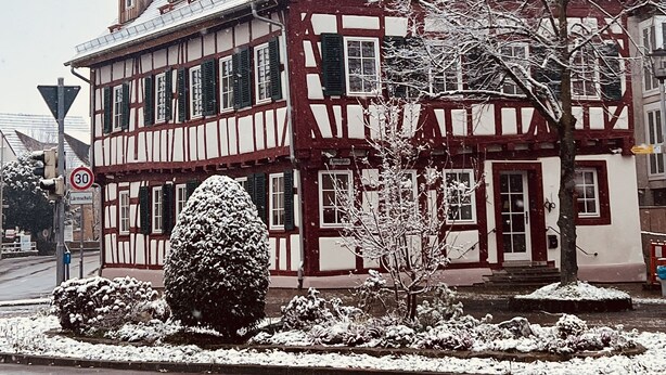 A traditional half-timbered building with multiple windows and a steeply pitched roof, surrounded by snow-covered trees and bushes. - Rose Boardinghouse (Grossbottwar)