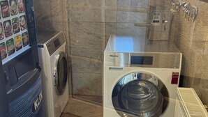 A compact laundry area with a front-loading Miele washing machine, a dryer, and a wall-mounted washing machine. - Rose Boardinghouse (Grossbottwar)