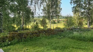 Een stenen muur met een grasveld en bomen op de achtergrond.
