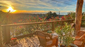 Un balcon avec des fauteuils en osier, une plante en pot et un sol carrelé.
