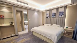 Habitación de hotel con cama, mesitas de noche, armario y baño visible a través de una puerta abierta.