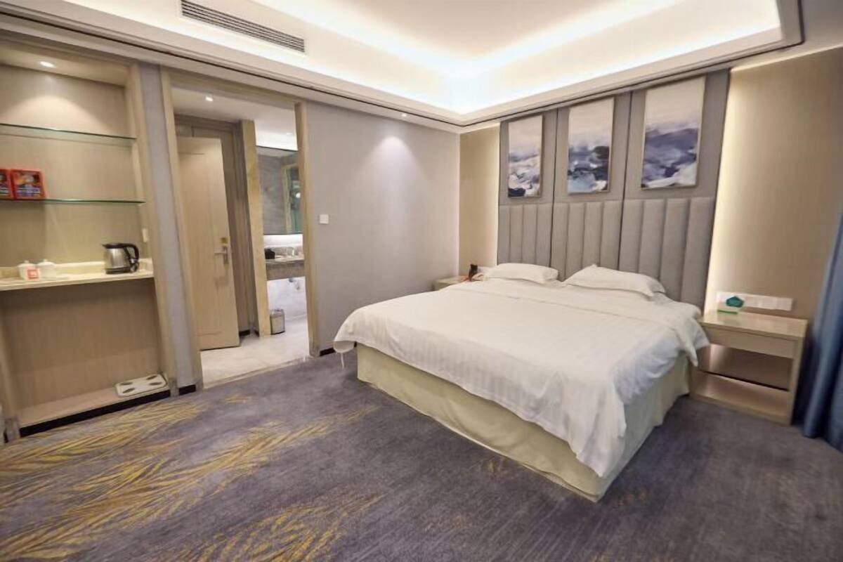 A hotel room with a bed, bedside tables, a wardrobe, and a bathroom visible through an open door.