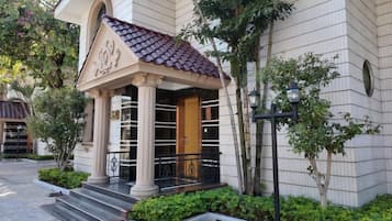 A building with a tiled roof, columns, and a wooden door.
