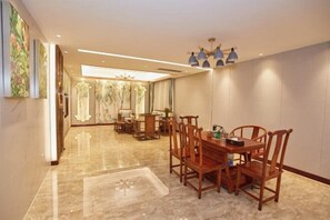 A dining area with a marble floor, wooden chairs, a round table, and a chandelier. - New Haojing Hotel (Guangzhou Xintang Metro Station) (Guangzhou)