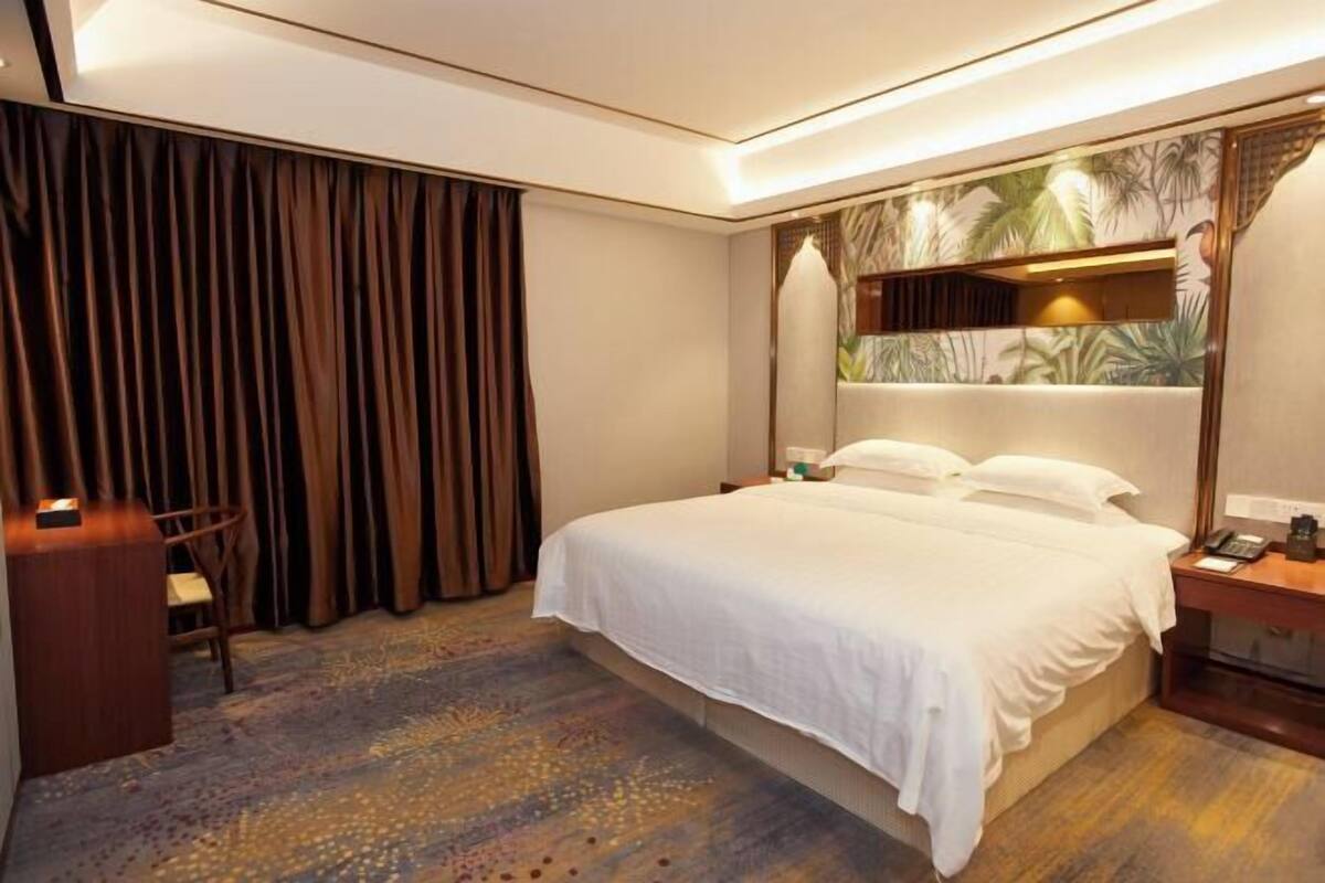 Una habitación de hotel con una cama grande, un escritorio, una silla y una cortina.