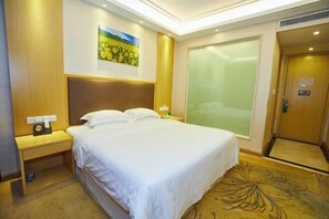 A hotel room with a large bed, a nightstand with a lamp, a painting on the wall, and a sliding door. - New Haojing Hotel (Guangzhou Xintang Metro Station) (Guangzhou)