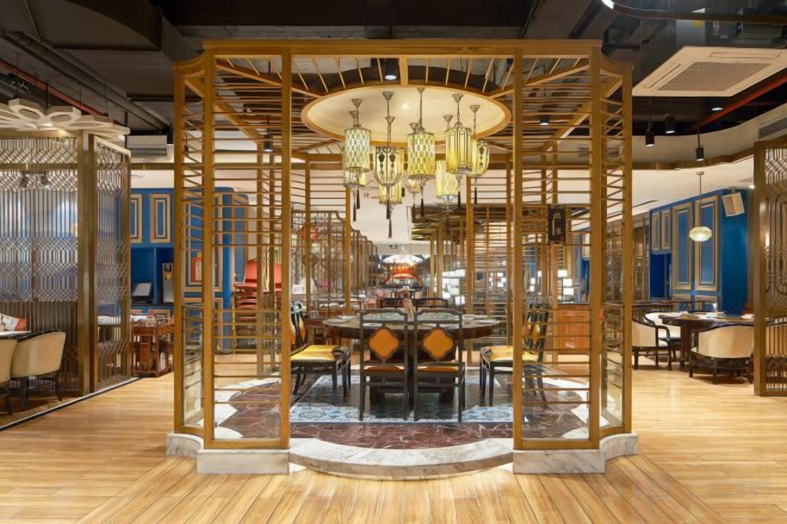Un comedor de estilo tradicional con una mesa redonda central, rodeada de sillas y un separador de madera decorativo.