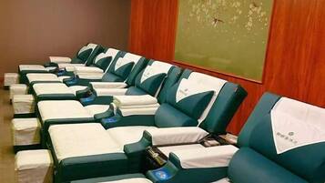A row of massage therapy chairs with footrests and a wooden wall with a floral mural.