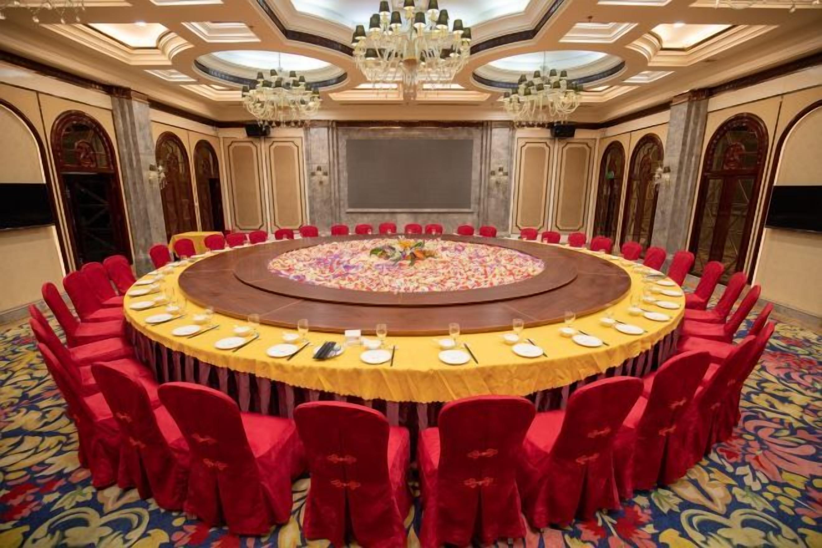 A conference room with a round table, red chairs, and a carpeted floor.