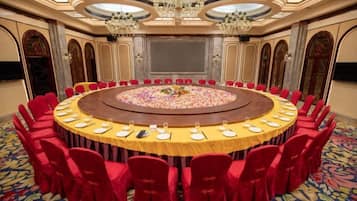 A conference room with a round table, red chairs, and a carpeted floor.