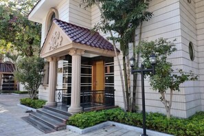 A building with a classic architectural style, featuring a prominent entrance with a tiled roof, columns, and a wooden door. - New Haojing Hotel (Guangzhou Xintang Metro Station) (Guangzhou)