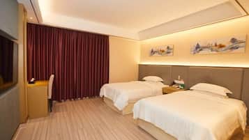 A hotel room with two beds, a desk, and a window with curtains.