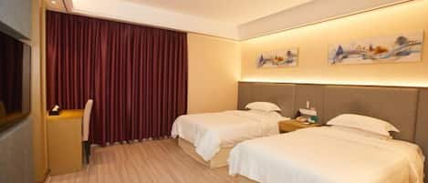 A hotel room with two beds, a desk, and a window with curtains.