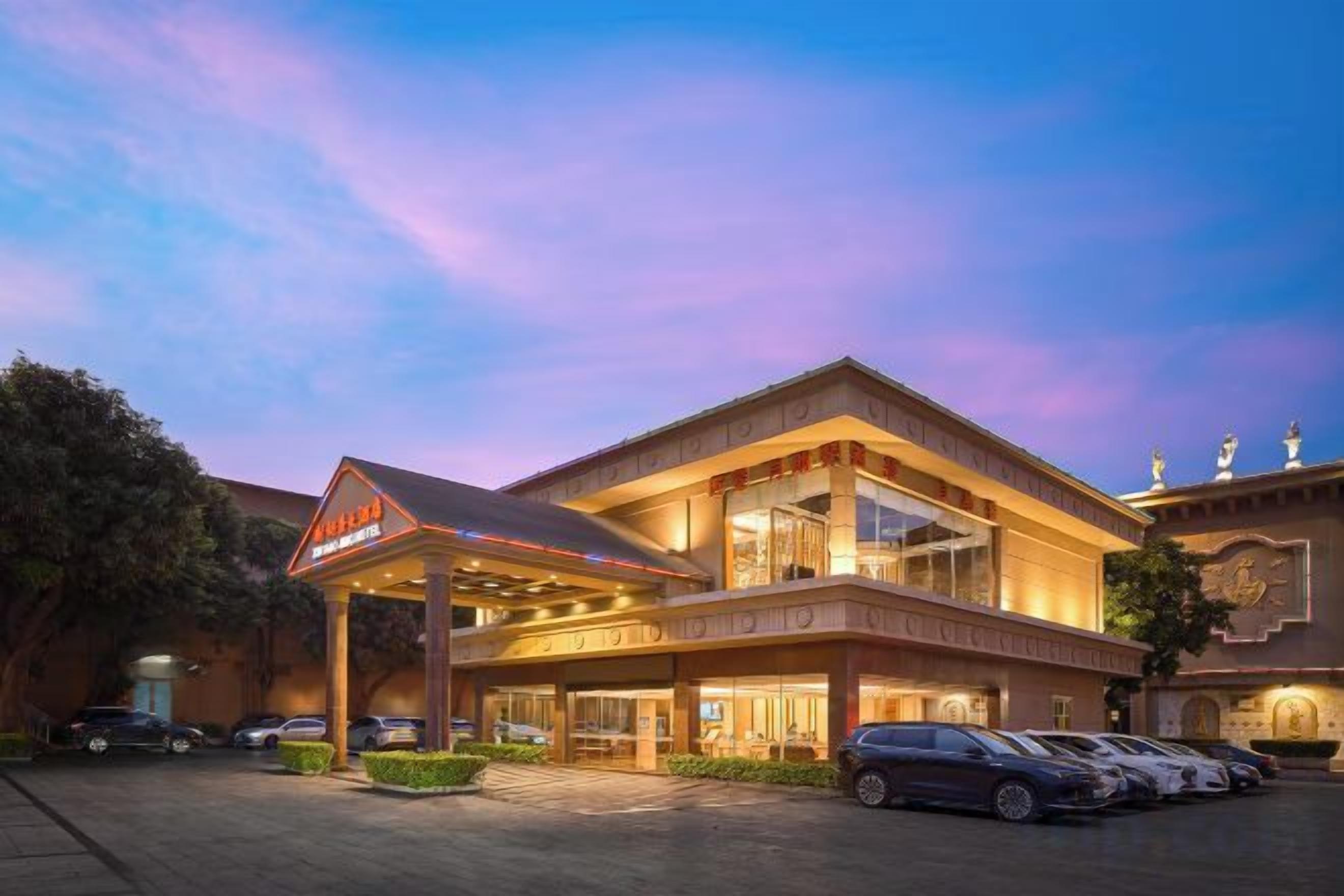 A hotel with a prominent entrance, multiple floors, and a parking area.