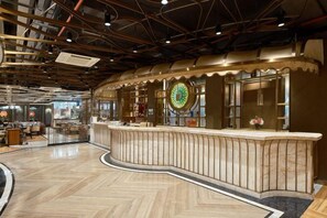 A spacious lobby with a curved reception desk, a large clock, and a herringbone floor pattern. - New Haojing Hotel (Guangzhou Xintang Metro Station) (Guangzhou)