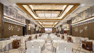 A banquet hall with round tables, white chairs, and a central aisle.