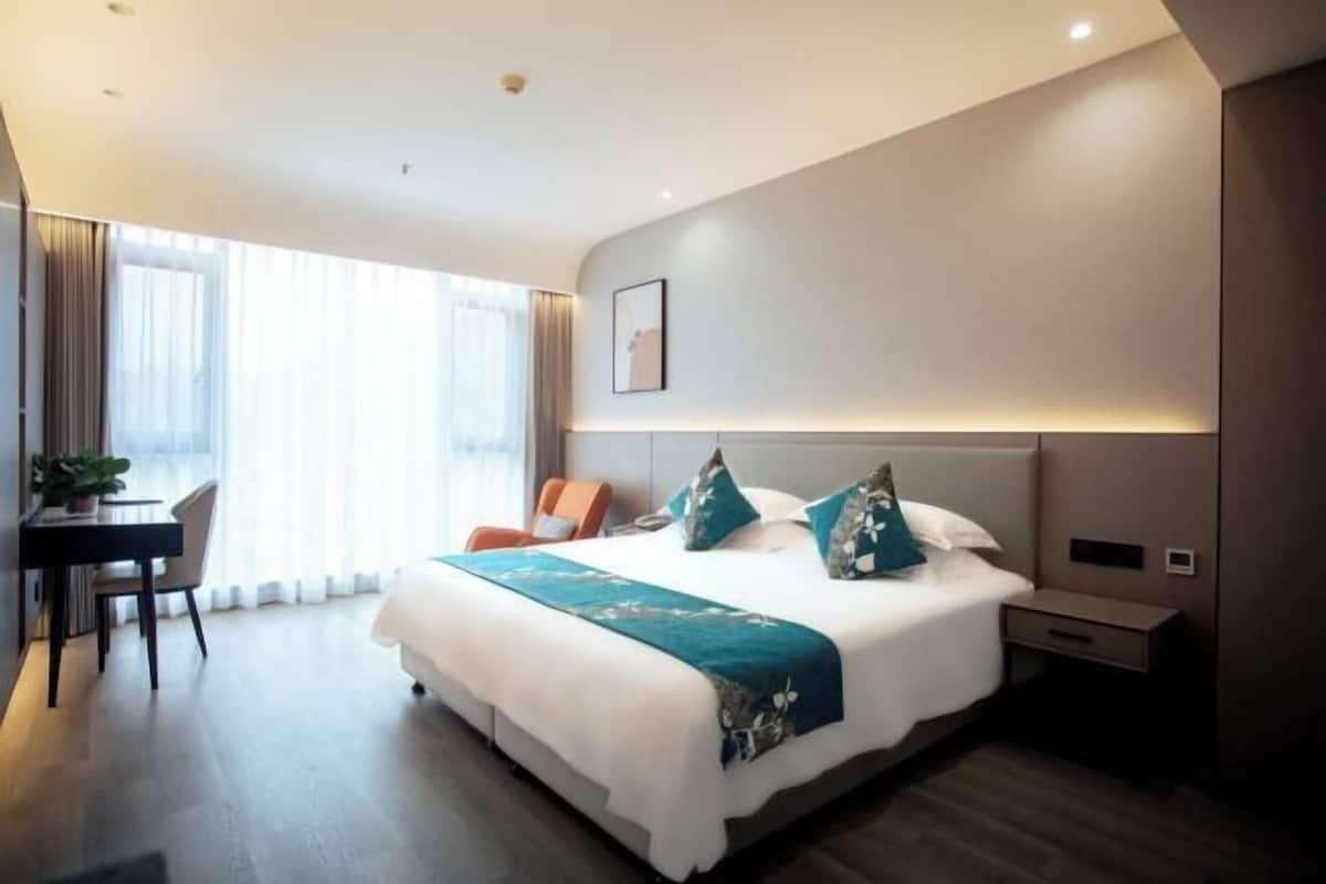 Una habitación de hotel moderna con una cama grande, un escritorio y una silla.