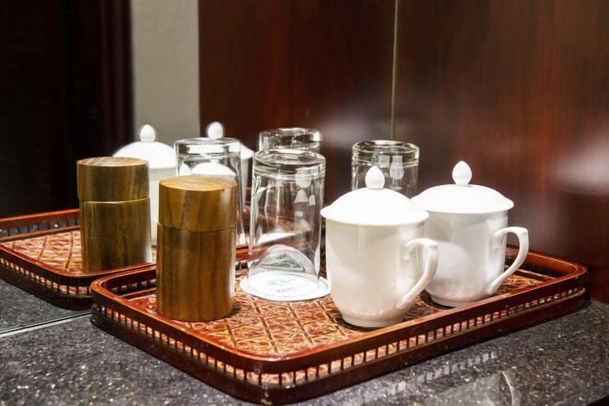 Un plateau contenant divers récipients en verre et des tasses en céramique blanche, probablement destinés à servir des boissons.